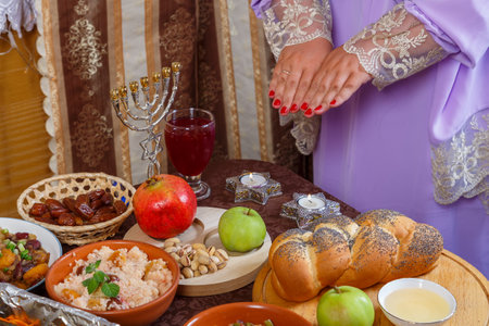 A Jewish woman reads a blessing on candles at a laid table on the Jewish holiday of Rosh Hashanah. horizontal photoの写真素材