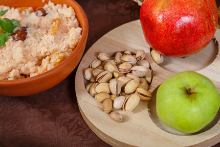 Festive set table for Rosh Hashanah with t ritual treats pomegranate nuts apple on a brown tablecloth. horizontal photoの写真素材