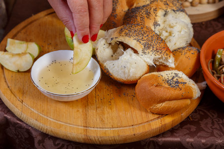 A woman's hand dips an apple in honey on the Jewish holiday of Rosh Hashanah. Horizontal photo.の写真素材