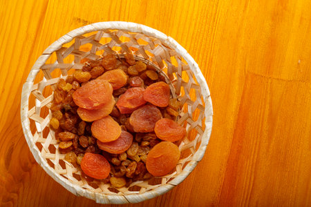 Dried apricots and raisins in a wicker plate on a wooden table after the end of Ramadan. Horizontal photo.の写真素材