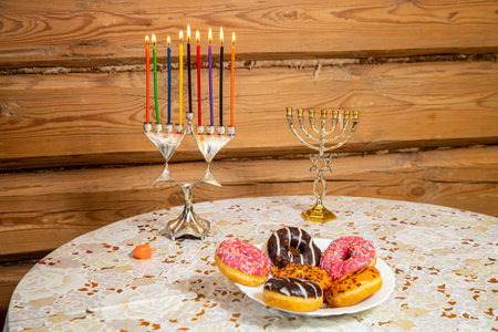 Donuts with glaze on a plate for the holiday of Hanukkah and a lit Hanukkiah with colored candles and a dreidel. horizontal photoの写真素材