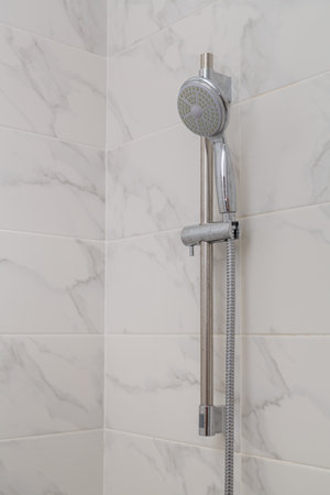 Shower tap mixer on a holder on the wall on tiles. Vertical photo
