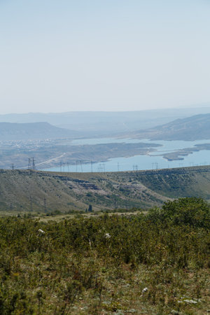 Power lines along the road against the backdrop of mountains and an azure lake. Vertical photoの写真素材