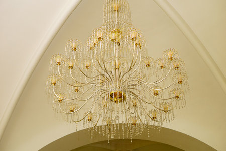 An antique chandelier in the center of the hall on a ceiling with stucco. Horizontal photo.の写真素材