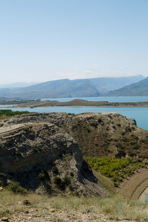 A reservoir against the backdrop of mountains with azure water on a sunny day peaks in a haze. Vertical photoの写真素材