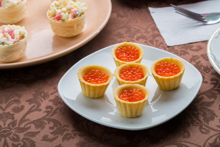 Red caviar in tartlets on a plate on a brown tablecloth. horizontal photoの写真素材