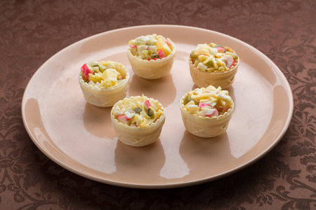 Salad in tartlets on a beige plate on a brown tablecloth. Medium planの写真素材