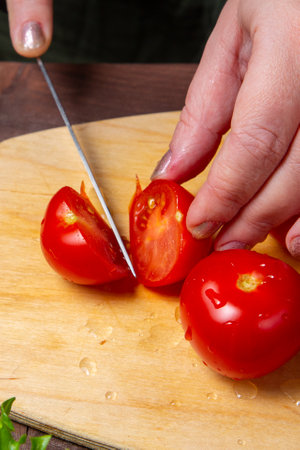 Cherry tomato is cut with a knife on a wooden board. Vertical photo.の写真素材