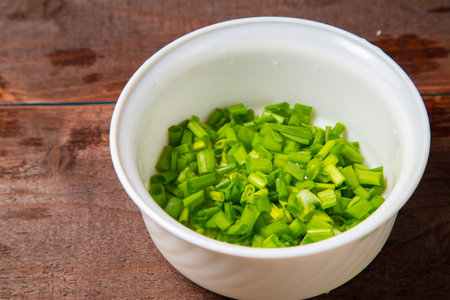Finely chopped green onions in a white salad bowl on the table. horizontal photoの写真素材