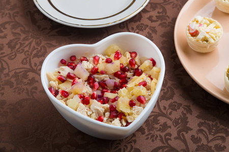 on the table there is a salad in tartlets and a salad with pomegranate in a heart-shaped plate. horizontal photoの写真素材