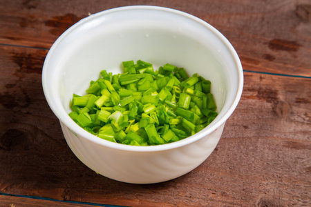 Finely chopped green onions in a white salad bowl on the table. horizontal photoの写真素材