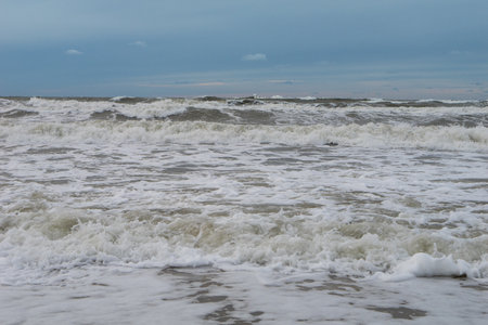 seashore on a cloudy day, strong waves, storm on the horizon, dark blue sky. horizontal photoの写真素材
