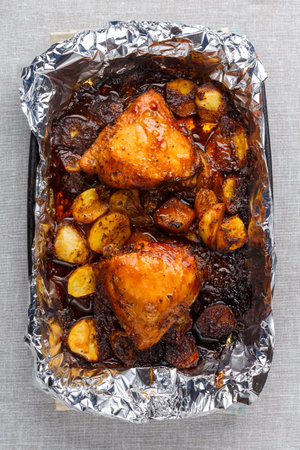 Chicken baked in sauce and spices with a golden brown crust in foil. Vertical photoの写真素材