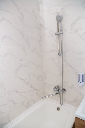 Shower tap mixer on a holder on the wall on tiles. Vertical photoの写真素材