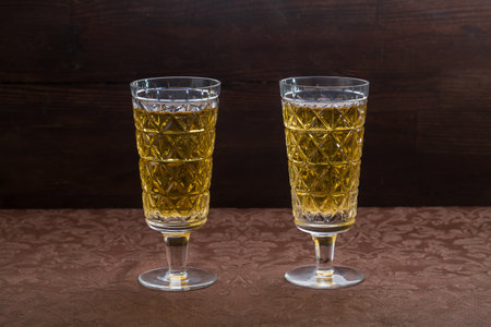 Sparkling champagne in two glasses on a brown tablecloth. Horizontal photo.の写真素材