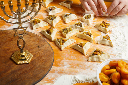 Women's hands mold triangle gomentashi cookies, a treat for the holiday of Purim. horizontal photoの写真素材