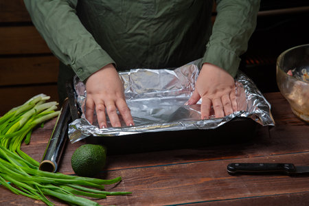 woman's hands line baking foil on a baking sheet. Horizontal photo.の写真素材