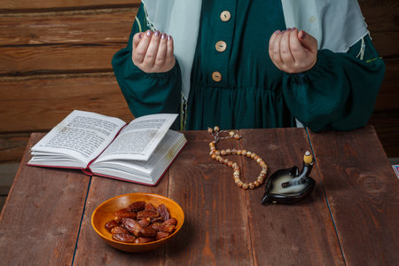 A Muslim woman prays at the table before the start of the Ramadan fast. Horizontal photo.の写真素材