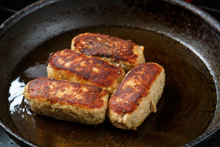 Lula cutlets fried in a frying pan with spices in oil. Horizontal photo.