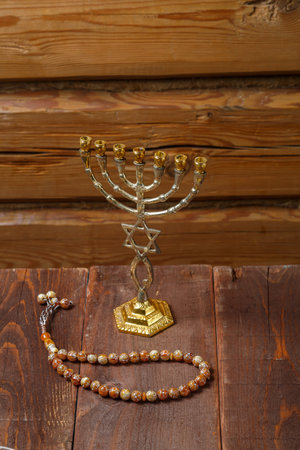 Menorah and rosary on a wooden table on a wooden wall. Vertical photo.