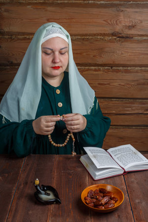 A Muslim woman prays at the table with a rosary in her hands before the end of the Ramadan fast on...