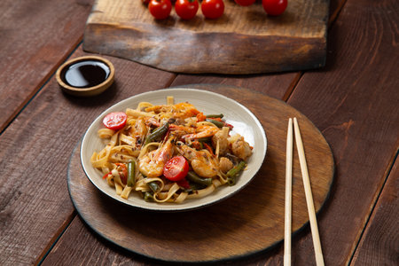 shrimp udon yaki soba sauce on a round stand next to soy sauce and chopsticks. horizontal photoの写真素材
