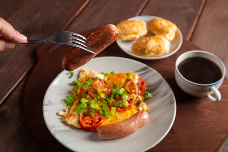 A stove with tomatoes and a sausage in a plate on a table of coffee and a croissant of a sausage on...