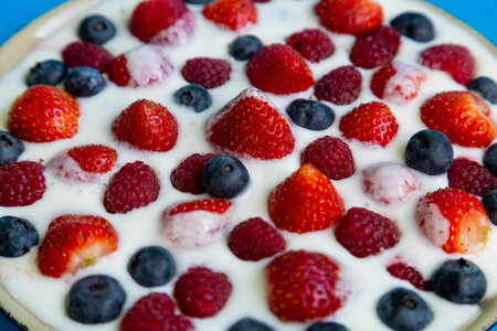 In a plate with freshly whipped cream juicy berries strawberries raspberries and blueberries close-up. Horizontal photo.の写真素材