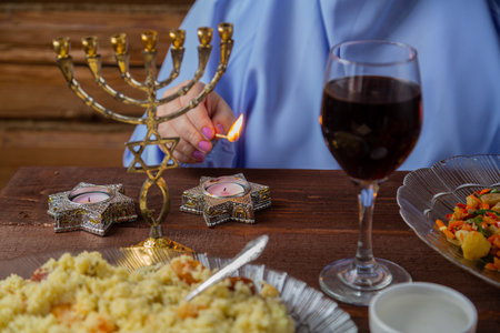 The hands of a Jewish woman light candles at the festive Pesach Seder table. Horizontal photo.