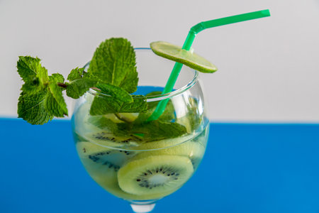 Glass with fruit cocktail kiwi mint lime with ice on wooden table. Horizontal photo.の写真素材
