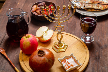 Challah, honey, pomegranate, apple and wine on a table with a menorah in honor of Rosh Hashanah. Horizontal photo.の写真素材