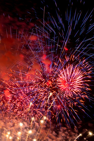 Multicolored colorful bright sparks of fireworks on the black sky. Vertical photo.の写真素材