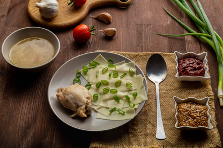 Dagestan national khinkal homemade dough, meat, thick broth, with mustard and adjika on the table next to a spoon. Horizontal photo.の写真素材