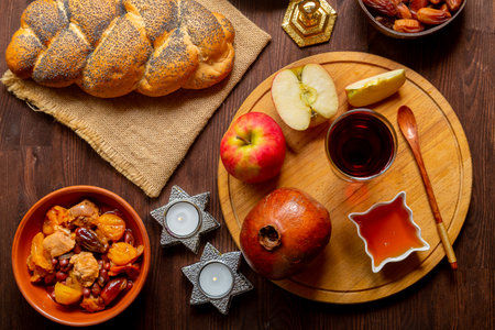 Challah, honey, apple and pomegranate and wine and chelnt with dried fruits on the table with...