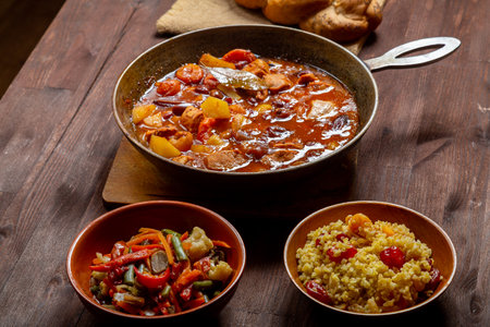 Hot thick cholent in a cast iron pan on the festive table for the meal on Rosh Hashanah. horizontal...
