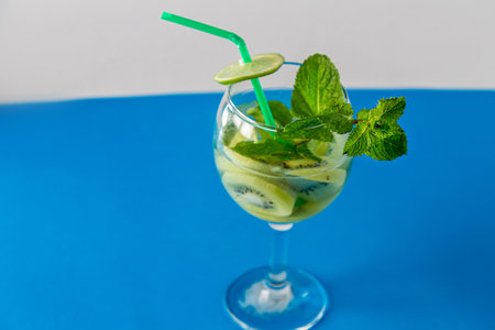 Glass with fruit cocktail kiwi mint lime with ice on blue background. Horizontal photo.の写真素材