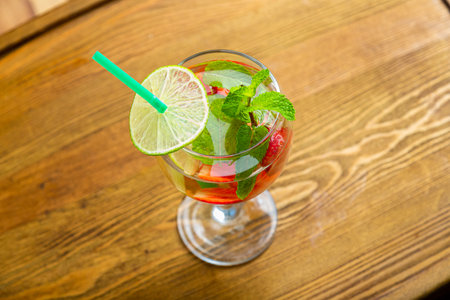 Glass with refreshing cocktail strawberry mint lime with ice on wooden table. Horizontal photo.の写真素材