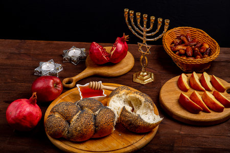 Challah, honey, apple and pomegranate and burning candles on wooden table with menorah Rosh Hashanah. horizontal photoの写真素材