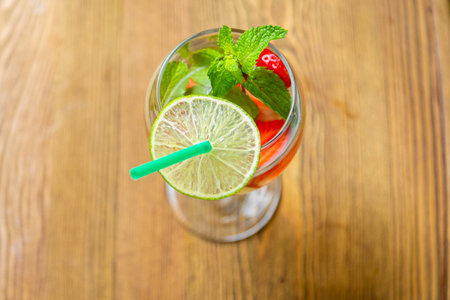 Non-alcoholic cocktail strawberry kiwi lime and mint in a glass with a straw on a wooden table. horizontal photoの写真素材