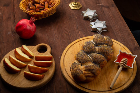 Homemade challah, honey, apple and pomegranate and burning candles on the table with a menorah Rosh Hashanah holiday. horizontal photoの写真素材