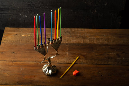 Hanukkiah with candles on the table in the semi-darkness next to the dreidel. Horizontal photo.の写真素材