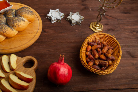 Homemade challah, honey, apple and pomegranate and burning candles on the table with a menorah Rosh Hashanah holiday. horizontal photoの写真素材