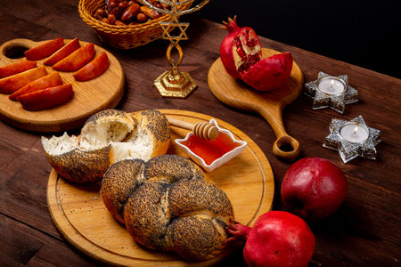 challah, honey, apple and pomegranate and burning candles on the table for Rosh Hashanah celebration. horizontal photoの写真素材