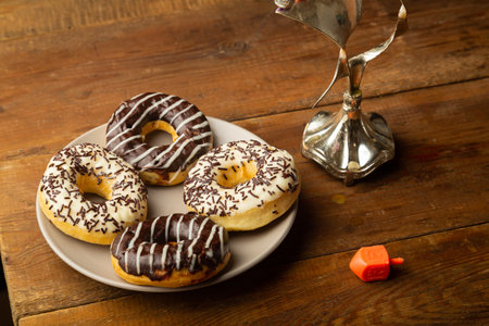 Chocolate glazed donuts on the table during the Hanukkah holiday next to a dreidel. Horizontal photo.の写真素材