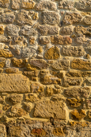 Ancient stone yellow wall of the fortress uneven rough texture. Vertical photo.の写真素材