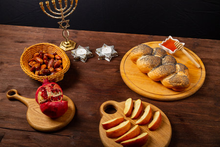 challah, honey, apple and pomegranate and burning candles on the table with a menorah for the Rosh Hashanah celebration. horizontal photoの写真素材