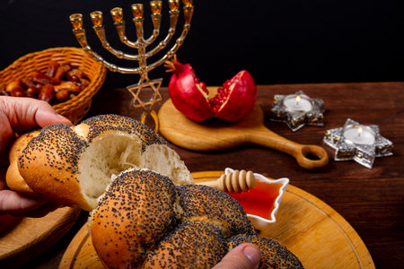 Broken challah, honey, apple and pomegranate and burning candles on wooden table with menorah Rosh Hashanah holiday. horizontal photoの写真素材