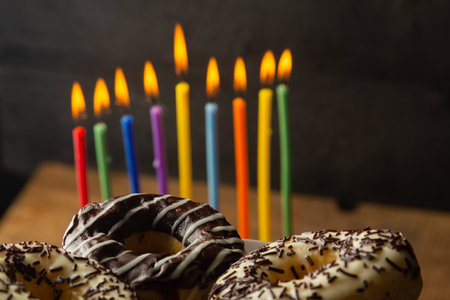 Hanukkiah with colored candles on the table and donuts in chocolate glaze. Horizontal photo.の写真素材