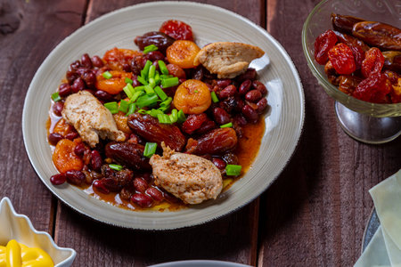 beans stewed with meat and dried fruits, spices and sauce and hummus on a wooden table. horizontal photoの写真素材