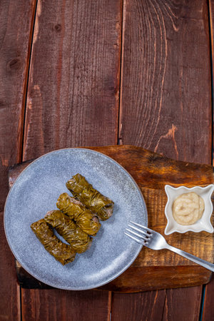 Dolma with beef on a wooden table in a plate next to the sauce. Copy space. Vertical photo.の写真素材